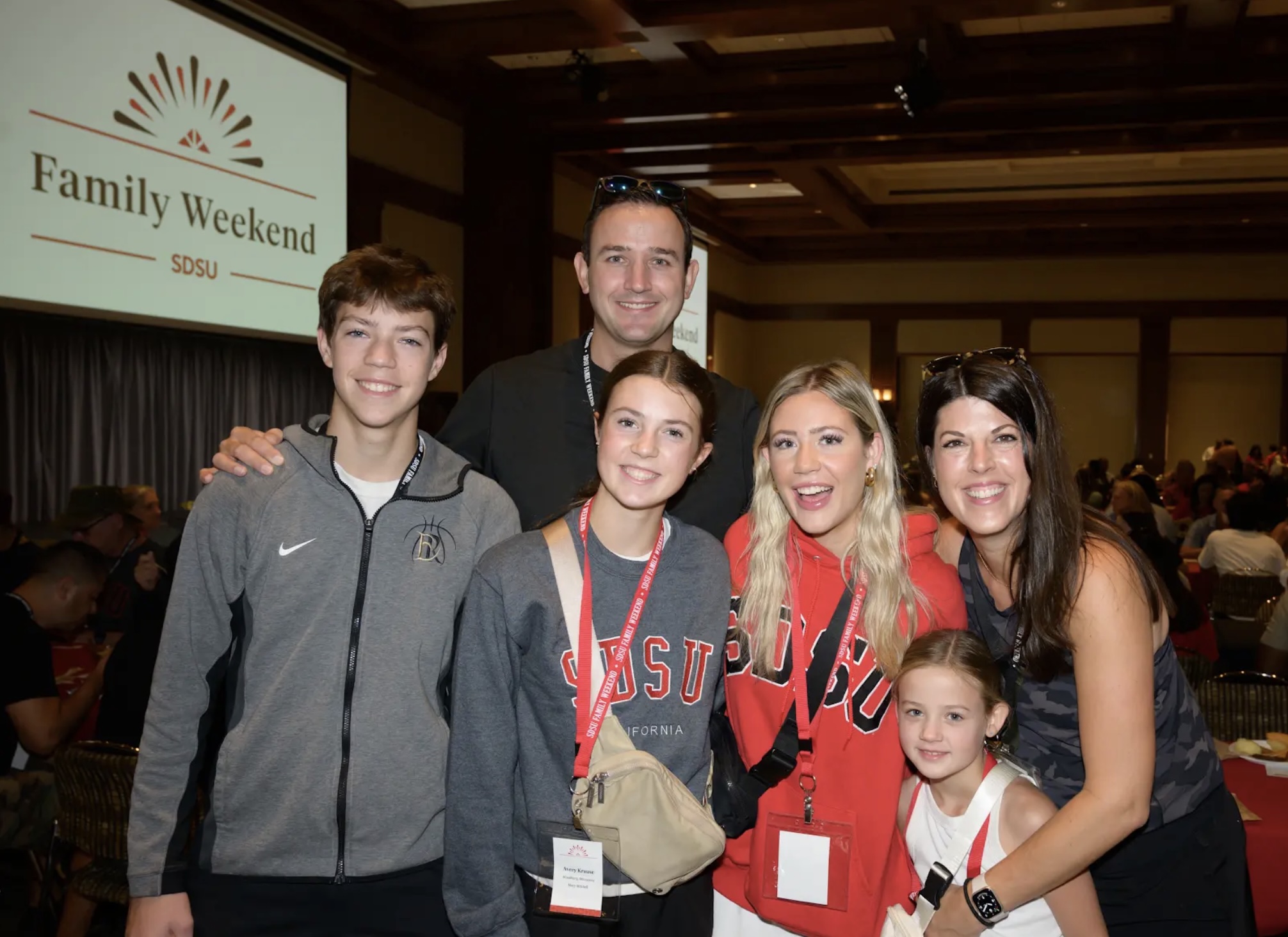 family in front of family weekend logo